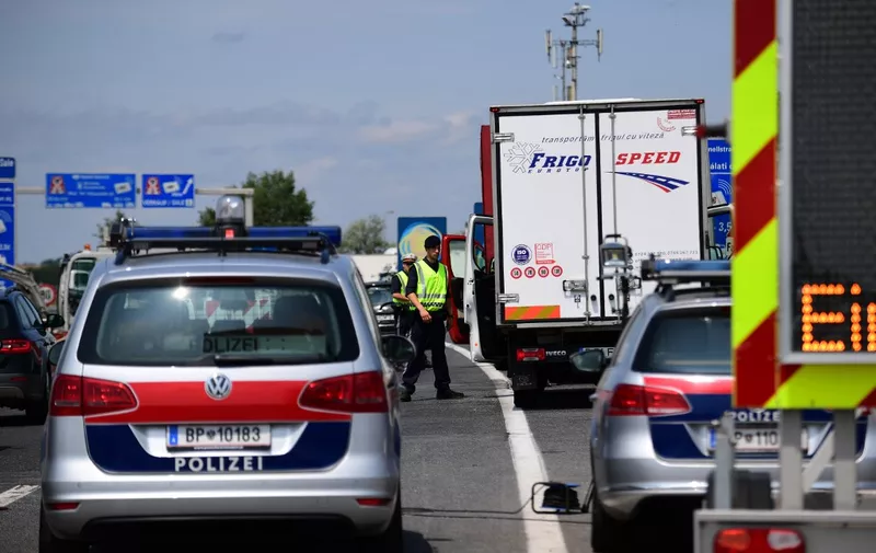 Austrian police officers direct cars and vans to a control at the Austrian-Hungarian border of Nickeldsdorf on July 12, 2016. - It's holiday season at Nickelsdorf on Austria's border with Hungary as families hit the highway but although the streams of refugees seen here a year ago have gone, things are far from normal. (Photo by ATTILA KISBENEDEK / AFP)