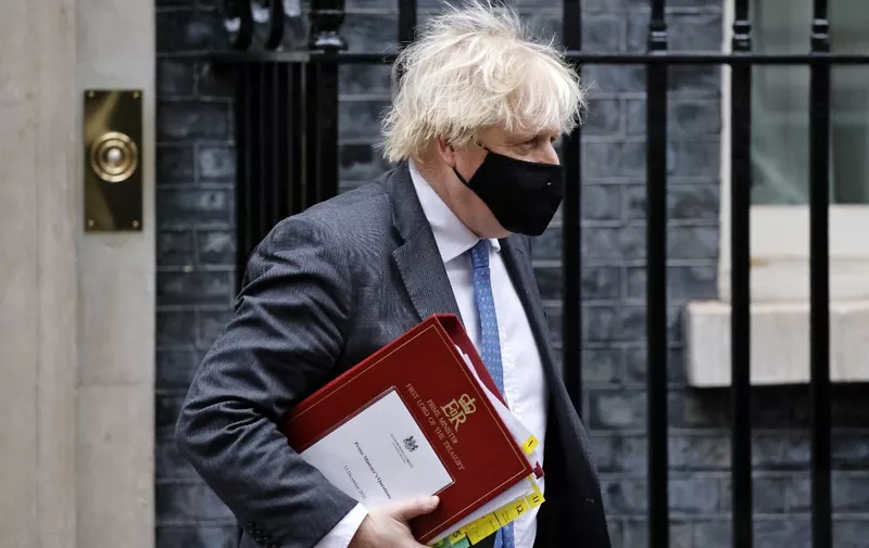 Britain's Prime Minister Boris Johnson, wearing a face covering to stop the spread of coronavirus, carries his notes in a ministerial folder as he leaves from 10 Downing Street in central London on December 15, 2021, to take part in the weekly session of Prime Minister Questions (PMQs) at the House of Commons. - Britain recorded nearly 60,000 new Covid-19 cases in the 24 hours to Tuesday -- one of its highest daily tallies of the pandemic -- as the Omicron coronavirus variant became the dominant strain in London. (Photo by Tolga Akmen / AFP)