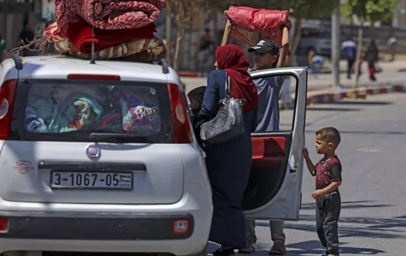 Members of a Palestinian family carry some of their belongings atop a car in Beit Hanun in the northern Gaza Strip, as they flee Israeli air and artillery strikes to a safer location, on May 14, 2021. - Israel pounded Gaza and deployed extra troops to the border as Palestinians fired barrages of rockets back, with the death toll in the enclave on the fourth day of conflict climbing to over 100. (Photo by MAHMUD HAMS / AFP)