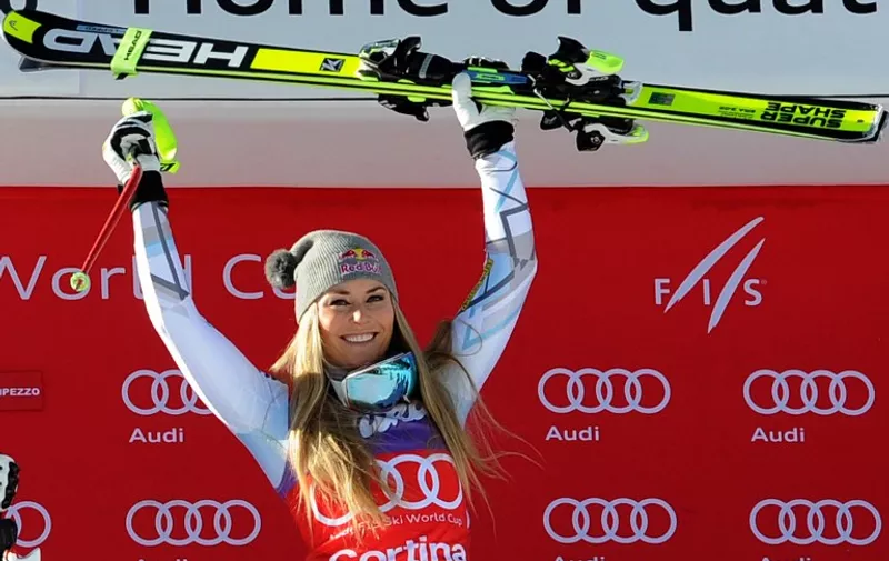 Winner US Lindsey Vonn celebrates on the podium of the FIS Alpine Skiing World Cup women's Downhill on January 23, 2016 in Cortina d'Ampezzo, northern Italy. American speed queen Lindsey Vonn bettered the record for the number of women's World Cup downhill victories when she won her 37th downhill race in Cortina on Saturday. Canada's Larisa Yurkiw got closest to Vonn finishing 0.28sec off the pace, with Swiss Lara Gut completing the podium, at 0.67sec.  AFP PHOTO / LUIGI FRACASSO / AFP / LUIGI FRACASSO