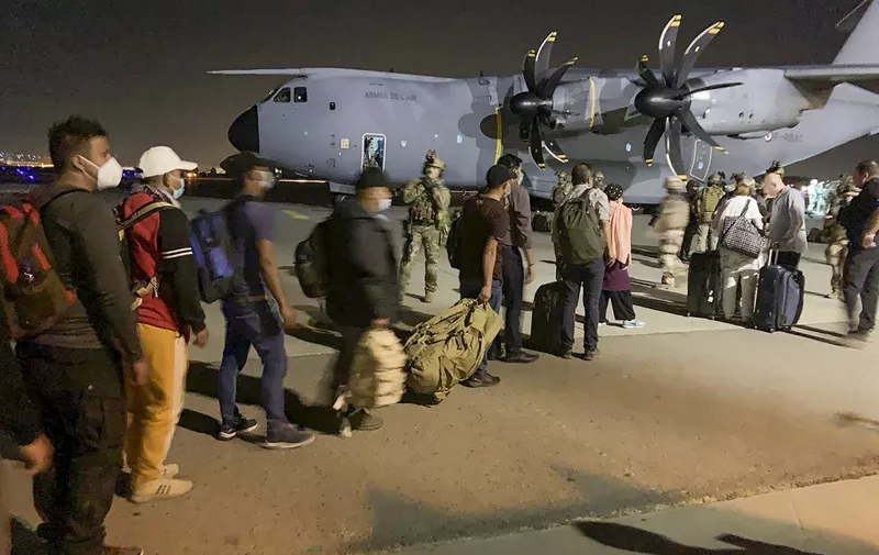 People line up to board a French military transport plane at the Kabul airport on August 17, 2021, for evacuation from Afghanistan after the Taliban's stunning military takeover of the country. (Photo by STR / AFP)