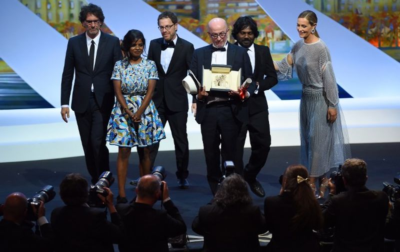 French director Jacques Audiard (C) poses on stage with US directors and Presidents of the Feature Film jury Joel (L) and Ethan Coen (3rdL), Sri Lankan actress Kalieaswari Srinivasan (2ndL), Sri Lankan actor Jesuthasan Antonythasan (2ndR) and Belgian actress Cecile de France after being awarded with the Palme d'Or from his film "Dheepan" during the closing ceremony of the 68th Cannes Film Festival in Cannes, southeastern France, on May 24, 2015. AFP PHOTO / ANNE-CHRISTINE POUJOULAT