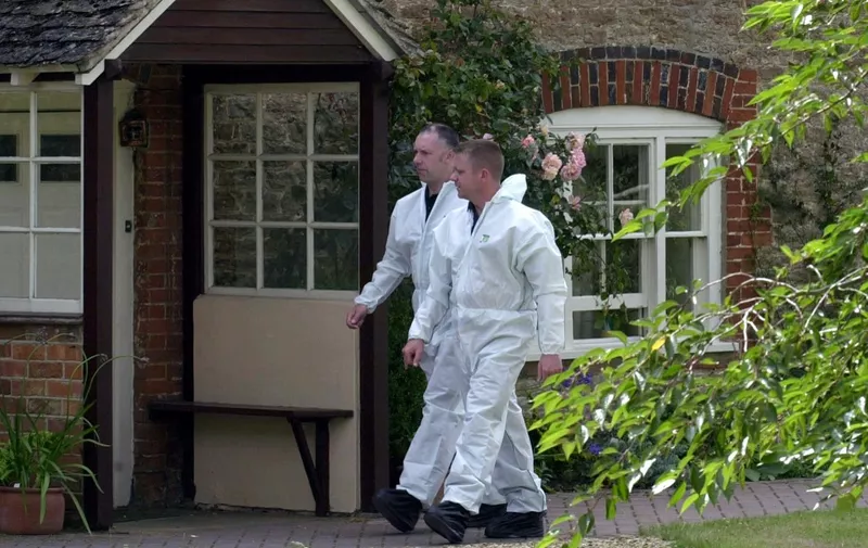 Police forensic officers walk in the garden of Dr.David Kelly home 19 July 2003 in the village of Longworth, Oxfordshire, a few kilometers from where Kelly's body was discovered Friday.  Kelly, a weapons control expert who worked for the Ministry of Defence, had been identified as a source for information to the BBC that the government deliberately exaggerated the threat posed by Saddam Hussein's regime. AFP PHOTO/ Martyn HAYHOW (Photo by MARTIN HAYHOW / AFP)