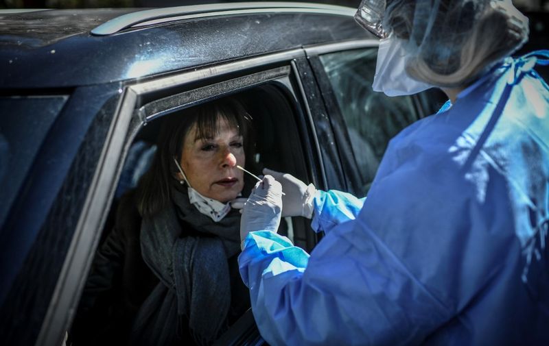 A nurse collects a sample from a person at a COVID-19 screening station outside the district hall of the 17th arrondissement in Paris, on March 30, 2020, on the fourteenth day of a lockdown aimed at curbing the spread of the COVID-19 (novel coronavirus) in France. (Photo by STEPHANE DE SAKUTIN / AFP)