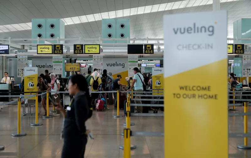 Passengers queue in front of check-in counters of Spanish low-cost airline Vueling at Barcelona's 'El Prat' airport on July 27, 2019. - A weekend strike by ground crew at Barcelona airport, Spain's second largest, has already forced the cancellation of over 100 flights. (Photo by PAU BARRENA / AFP)