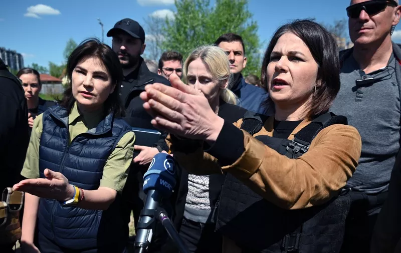German Foreign Minister Annalena Baerbock (R) and Ukraine's Prosecutor General Iryna Venediktova (L) attend outside St. Andrew and Pyervozvannoho All Saints church at the former mass grave of civilian people in the Ukrainian town of Bucha, northwest of Kyiv on May 10, 2022. - German Foreign Minister Annalena Baerbock attends a surprise trip to Ukraine on May 10, 2022 visited Bucha, a suburb of Kyiv where Russian troops have been accused of killing civilians. (Photo by SERGEY VOLSKIY / AFP)