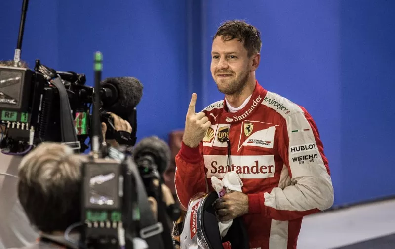 Ferrari's German driver Sebastian Vettel celebrates after taking pole position in the qualifying session of the Formula One Singapore Grand Prix in Singapore on September 19, 2015. AFP PHOTO / Philippe Lopez