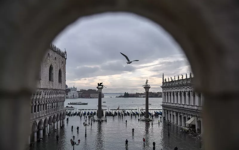 A general view shows the Doge's Palace (L) overlooking the flooded St. Mark's Square, the Lion of St. Mark winged bronze statue (Rear L), gondolas and the Venetian lagoon in the distance after an exceptional overnight "Alta Acqua" high tide water level, on November 13, 2019 in Venice. - Venice was hit by the highest tide in more than 50 years late November 12, with tourists wading through flooded streets to seek shelter as a fierce wind whipped up waves in St. Mark's Square. (Photo by Marco Bertorello / AFP)