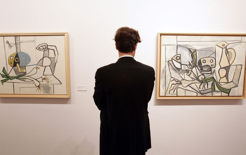 A visitor looks at "Nature morte a la tete de mort cruche, poireaux" (L) and "Nature morte aux poireaux tete de poisson, crane et pichet" by painter Pablo Picasso on display at the Palazzo Grassi in Venice 09 November 2006 as part of the "Picasso, la joie de vivre, 1945-1948" exhibition. The exhibition is dedicated to a four year period in Picasso's life, in the immediate postwar. Some 200 of Picasso's works are on display, including paintings, drawings, marble incisions, sculptures, and pottery. Numerous works belonging to private and public collections and 120 masterpieces from The Picasso Museum collection in Antibes. The exhibition. will be open to the pubblic  from 11 November 2006 to 11 March 2007.    AFP PHOTO / ALBERTO PIZZOLI (Photo by ALBERTO PIZZOLI / AFP)
