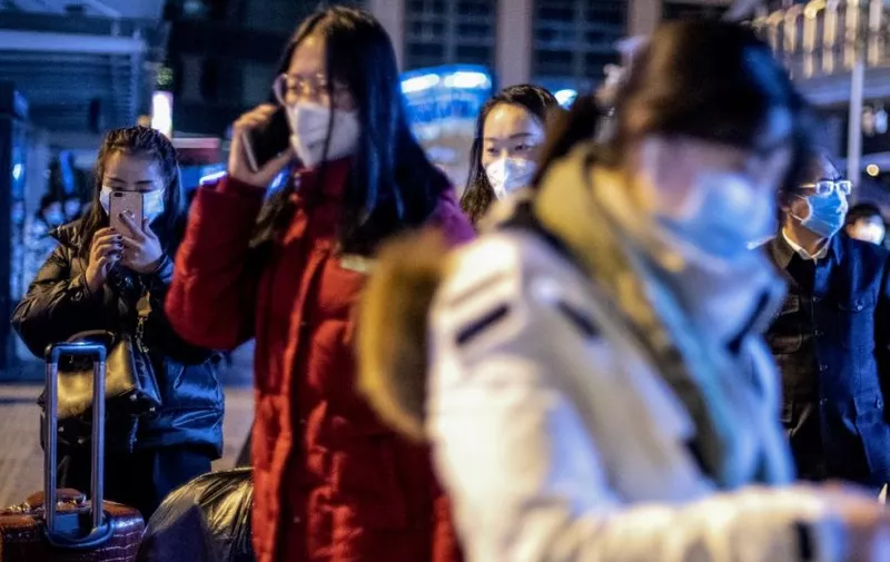 People wearing protective masks arrive at Beijing railway station ahead of the Lunar New Year in Beijing on January 23, 2020. - China is halting public transport and closing highway toll stations in two more cities in Hubei province, the epicentre of a deadly virus outbreak, authorities said on January 23. (Photo by NOEL CELIS / AFP)