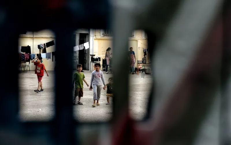 Children are pictured through the gate of the courtyard of an abandoned school used by volunteers for hosting Syrian and Afghan refugees in Athens on July 1, 2016.
Some 250 people live in self-management in the school of Athens city center, closed for three years. The families occupy three floors of the building, and twenty classrooms, where a tense sheets forest delineate areas of life and protect privacy. The squat was established in mid-March, when the sudden closure of their borders with the countries north of Greece makes it a trap for those who relied only cross to reach Germany or Sweden. Almost all e now living in dozens of camps set up in haste by the government. Some rent rooms. The others are squat. The government estimates about 1,500 the number of people living well into "outdoor hospitality structures." / AFP PHOTO / ARIS MESSINIS