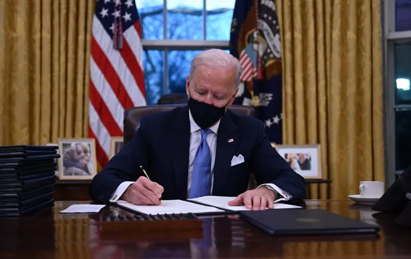 US President Joe Biden sits in the Oval Office as he signs a series of orders at the White House in Washington, DC, after being sworn in at the US Capitol on January 20, 2021. - US President Joe Biden signed a raft of executive orders to launch his administration, including a decision to rejoin the Paris climate accord. The orders were aimed at reversing decisions by his predecessor, reversing the process of leaving the World Health Organization, ending the ban on entries from mostly Muslim-majority countries, bolstering environmental protections and strengthening the fight against Covid-19. (Photo by Jim WATSON / AFP)