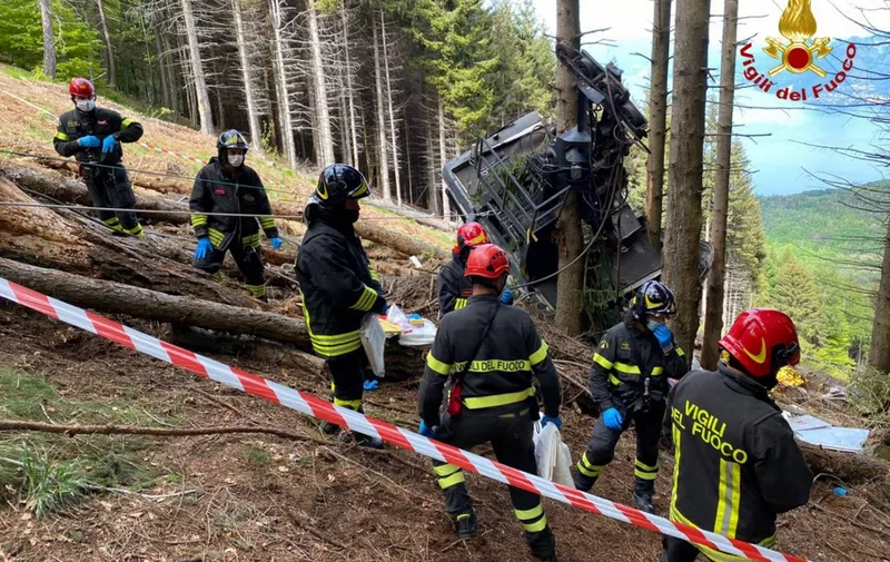 A photo taken and handout on May 23, 2021 by The Italian Firefighters "Vigili del Fuoco" shows rescuers by a cable car that crashed to the ground in the resort town of Stresa on the shores of Lake Maggiore in the Piedmont region. - 13 people died and two children were seriously injured Sunday after a cable car crashed to the ground in northern Italy, emergency services said. (Photo by Handout / Vigili del Fuoco / AFP) / RESTRICTED TO EDITORIAL USE - MANDATORY CREDIT "AFP PHOTO / VIGILI DEL FUOCO / HANDOUT " - NO MARKETING - NO ADVERTISING CAMPAIGNS - DISTRIBUTED AS A SERVICE TO CLIENTS