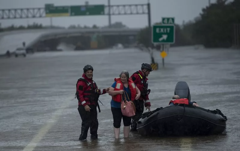 A woman is helped out of a Houston Police dive team boat after being rescued from the Meyerland area during the aftermath of Hurricane Harvey August 27, 2017 in Houston, Texas.
Hurricane Harvey left a trail of devastation Saturday after the most powerful storm to hit the US mainland in over a decade slammed into Texas, destroying homes, severing power supplies and forcing tens of thousands of residents to flee. / AFP PHOTO / Brendan Smialowski