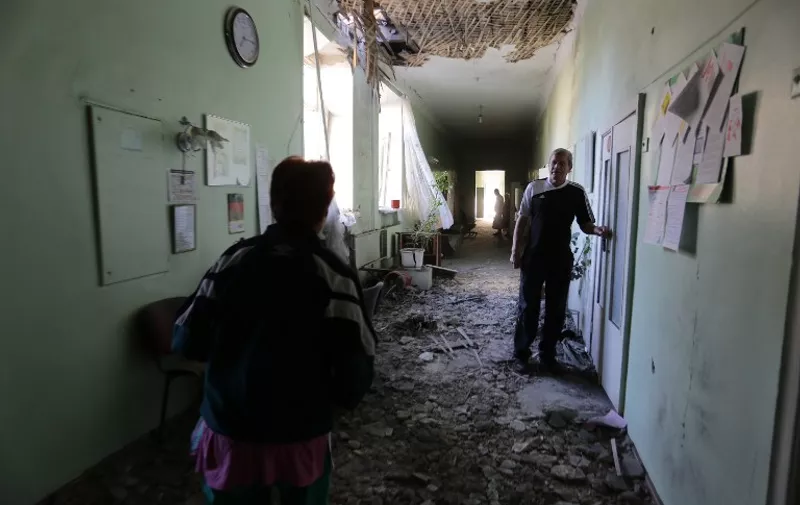 A patient (R) stands in a hospital destroyed as a result of shelling between Ukrainian forces and pro-Russian separatists in the eastern Ukrainian city of Donetsk on July 19, 2015. Russian Foreign Minister Sergei Lavrov held separate talks on JUly 18 with his Ukraine, US and German counterparts, the Kremlin announced, as fighting spikes in eastern Ukraine. AFP PHOTO/  ALEKSEY FILIPPOV