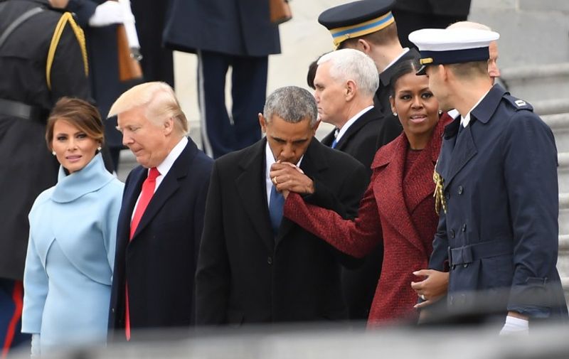 Former President Barack Obama(C) kisses the hand of Michelle Obama as US President Donald Trump and First Lady Melania Trump(L) escort them to a waiting helicopter to depart the US Capitol after inauguration ceremonies at the US Capitol in Washington, DC, on January 20, 2017. / AFP PHOTO / JIM WATSON