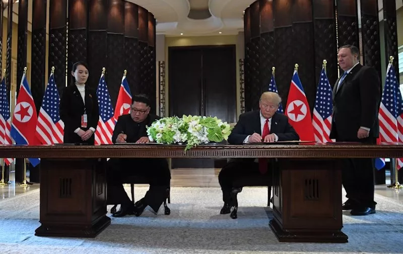 US President Donald Trump (2nd R) and North Korea's leader Kim Jong Un (2nd L) sign documents as US Secretary of State Mike Pompeo (R) and the North Korean leader's sister Kim Yo Jong (L) look on at a signing ceremony during their historic US-North Korea summit, at the Capella Hotel on Sentosa island in Singapore on June 12, 2018.

Donald Trump and Kim Jong Un became on June 12 the first sitting US and North Korean leaders to meet, shake hands and negotiate to end a decades-old nuclear stand-off. / AFP PHOTO / SAUL LOEB