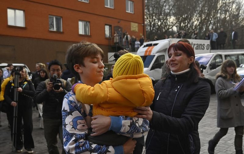 Inessa meets her son Vitaly after the bus delivering him and more than a dozen other children back from Russian-held territory arrived in Kyiv on March 22, 2023. More than 16,000 Ukrainian children have been deported to Russia since the February 24, 2022 invasion, according to Kyiv, with many allegedly placed in institutions and foster homes. (Photo by SERGEI CHUZAVKOV / AFP)