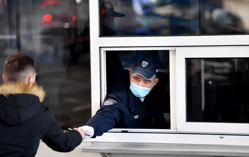 A Serbian border police officer wearing a protective mask checks documents of a traveller on March 15, 2020, at the Batrovci border crossing between Serbia and Croatia. - Currently there are 46 positive cases of coronavirus COVID-19 in the Republic of Serbia. Serbian government temporarily prohibits the entry of foreign nationals arriving from countries particularly affected by the virus. Serbian nationals coming from the affected area go to a mandatory solitary confinement at home, under medical supervision, for 14 days. Previously indoor mass events are cancelled, and no spectators at sporting events. The government has "temporarily closed" 44 border crossings (the main ones remain open), to road, rail and river traffic. (Photo by Andrej ISAKOVIC / AFP)