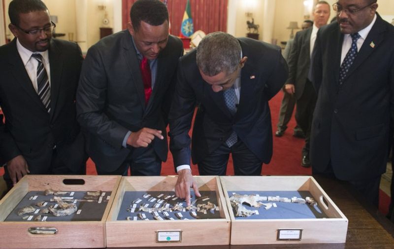 US President Barack Obama (2nd R) touches a bone fragment of "Lucy", who was estimated to have lived 3,2 million years ago, alongside Ethiopian Prime Minister Hailemariam Desalegn (R) and Zeresenay Alemseged (2nd L), head of the California Academy of Sciences, prior to a State Dinner at the National Palace in Addis Ababa, Ethiopia, on July 27, 2015. Discovered in 1974 by American anthropoligist Ronald Johanson in Ethiopia, several hundred pieces of bone represent about 40 percent of the skeleton of a female body providing a unique look at human evolution. AFP PHOTO / SAUL LOEB