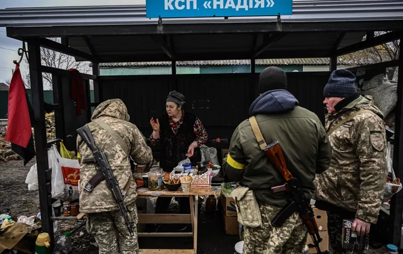 A woman cooks for Ukrainian soldiers at a frontline, northeast of Kyiv on March 3, 2022. - A Ukrainian negotiator headed for ceasefire talks with Russia said on March 3, 2022, that his objective was securing humanitarian corridors, as Russian troops advance one week into their invasion  of the Ukraine. (Photo by Aris Messinis / AFP)