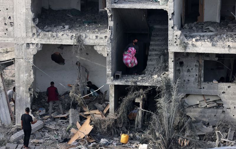 People salvage some belongings from a damaged building following Israeli bombing on Rafah in the southern Gaza Strip, on November 11, 2023, as battles between Israel and the Palestinian Hamas movement continue. (Photo by SAID KHATIB / AFP)