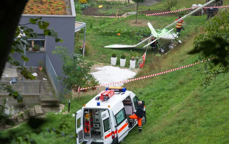 Swiss police officers inspect the wreckage of a plane involved in a collision with a second plane during an airshow on August 23, 2015 in Dittingen, near Basel, northern Switzerland. According to a Swiss news agency, a pilot died and the second pilot --both from the Wurttemberg state in Germany-- managed to eject and parachute himself to land safely. AFP PHOTO / SEBASTIEN BOZON