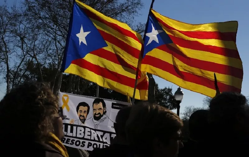 People hold Catalan pro-independence 'Estelada' flags and a flag depecting images of Catalan separatist leaders Jordi Cuixart and Jordi Sanchez outside Catalan's parliament during its inaugural session on January 17, 2018 in Barcelona. 

Catalonia's parliament met for the first time since it was dissolved following a failed bid to break from Spain in a session that will see separatists start the process to get sacked regional leader Carles Puigdemont back into power.  / AFP PHOTO / Pau Barrena