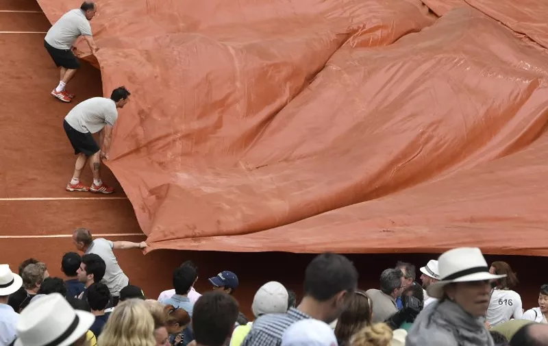 The court is covered as rain starts during the men's semi-final match between Novak Djokovic and Great Britain's Andy Murray at the Roland Garros 2015 French Tennis Open in Paris on June 5, 2015. AFP PHOTO / DOMINIQUE FAGET