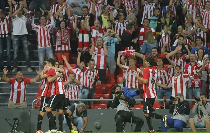 Athletic Bilbao's forward Aritz Aduriz (L) is congratulated by teammates after scoring their team's fourth goal  during the Spanish Supercup first-leg football match Athletic Club Bilbao vs FC Barcelona at the San Mames stadium in Bilbao on August 14, 2015.  AFP PHOTO/ ANDER GILLENEA