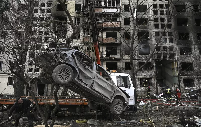 A crane removes a ruined car from in front of a destroyed apartment building after it was shelled in the northwestern Obolon district of Kyiv on March 14, 2022. - Two people were killed on March 14, 2022, as various neighbourhoods of the Ukraine capital Kyiv came under shelling and missile attacks, city officials said, after the Russia's military invaded the Ukraine on February 24, 2022. (Photo by Aris Messinis / AFP)