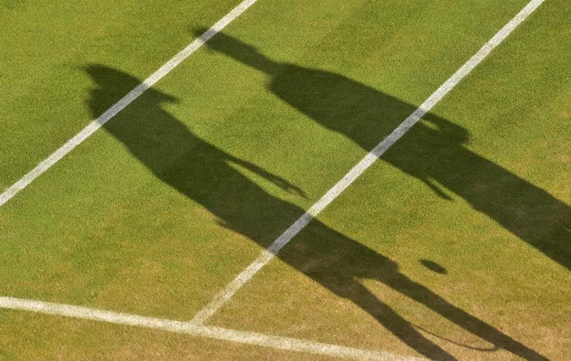 (FILES) This file photo taken on July 7, 2015 shows 
the shadow of two tennis players on day eight of the 2015 Wimbledon Championships at The All England Tennis Club in Wimbledon.
A widespread investigation into corruption in the heart of world tennis has been released on January 18, 2016 as damning evidence has found a large net smuggled into the centre of a number of tennis facilities around the world. Reports by satirical new services Buzzfeed and the BBC have claimed a link between the net scandal and various large bets made on contentious games. / AFP / LEON NEAL