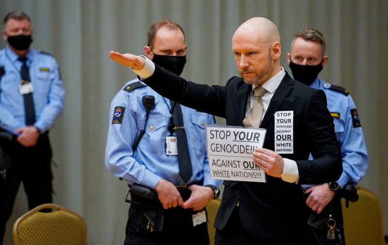 Anders Behring Breivik raises his arm to make a Nazi salute as he arrives on the first day of the trial where he is requesting release on parole, on January 18, 2022 at a makeshift courtroom in Skien prison, Norway. - The mass murderer Anders Behring Breivik, who now calls himself Fjotolf Hansen, was in 2012 sentenced to a at least 21 years inprisonment. Under Norwegian law, Breivik is entitled to a review in court after the initial term of 10 years. 77 people lost their lives in the attacks that took place in Oslo and Utøya (Utoya) on July 22, 2011. (Photo by Ole Berg-Rusten / NTB / AFP) / Norway OUT