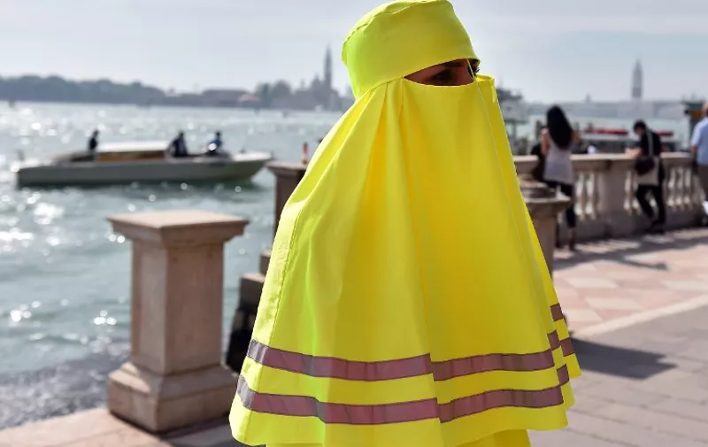 A woman wears a yellow burqa during the artistic performance "High Visibility Burqa" in Venice on May 6, 2015 at the entrance of the 56th International Art Exhibition (Biennale d'Arte) titled "All the Worlds Futures". AFP PHOTO / GABRIEL BOUYS