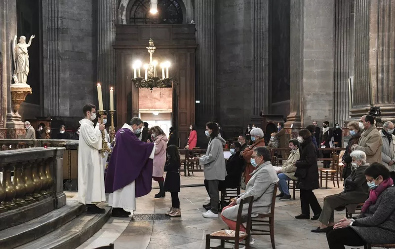 People attend a service at the Saint-Sulpice church in Paris on November 29, 2020 as mass resume in France following the government's ease of Covid-19 lockdown restrictions with only 30 people allowed per church. (Photo by ALAIN JOCARD / AFP)