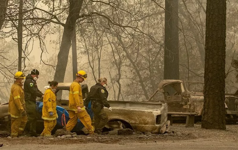 (FILES) In this file photo taken on November 14, 2018 Rescue workers carry a body away from a burned property in the Holly Hills area of Paradise, California/ - The fire that has ravaged northern California is now almost completely contained, authorities said on November 22, 2018, as the death toll rose to 84. The number of people listed as unaccounted for in the deadliest and most destructive fire in state history stands at 563. (Photo by Josh Edelson / AFP) / ALTERNATIVE CROP