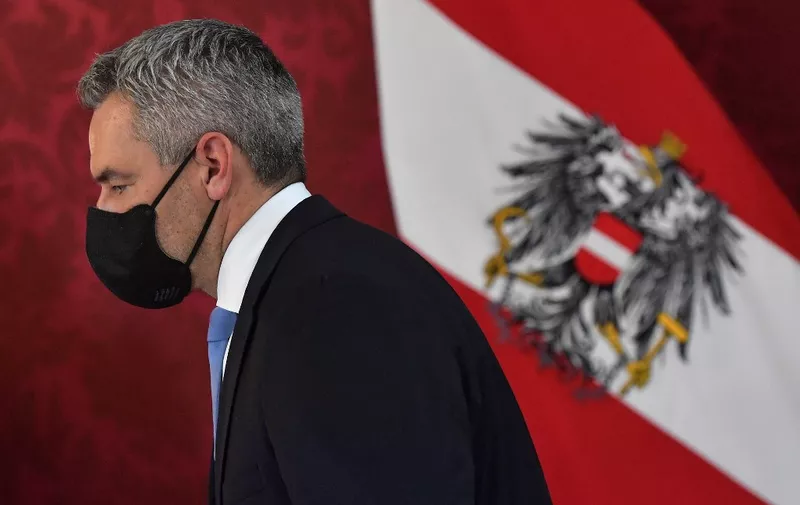 Newly appointed Austria's Chancellor Karl Nehammer walks past an Austrian flag during a swearing-in ceremony of the new Chancellor in Vienna, Austria on December 6, 2021. - Austria's Interior Minister Karl Nehammer is due to be sworn in as the country's third chancellor in as many months on December 6, capping a turbluent few days in the country's politics. (Photo by JOE KLAMAR / AFP)