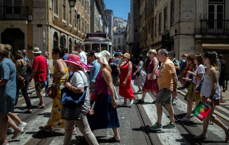 People walk down Rua Augusta street in downtown Lisbon on May 28, 2022. (Photo by CARLOS COSTA / AFP)