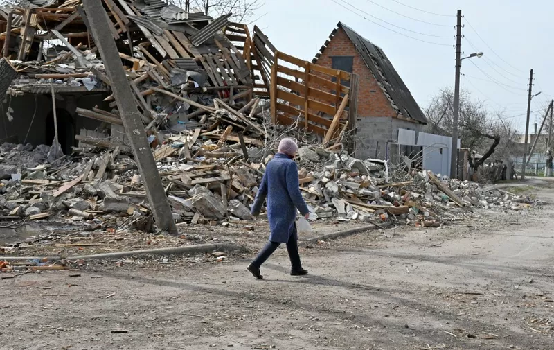 A Ukrainian woman walks past a collapsed house in the outskirts of Chuguiv, Kharkiv region on April 8, 2022. (Photo by SERGEY BOBOK / AFP)