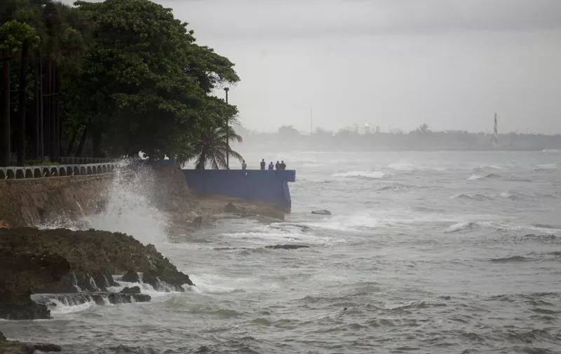 People stand by the sea in the rain in the La Cienaga neighborhood on September 7, 2017, as Hurricane Irma approaches. 
Irma was packing maximum sustained winds of up to 185 mph (295 kph) as it followed a projected path that would see it hit the northern edges of the Dominican Republic and Haiti on Thursday, continuing past eastern Cuba before veering north for Florida.  / AFP PHOTO / Erika SANTELICES