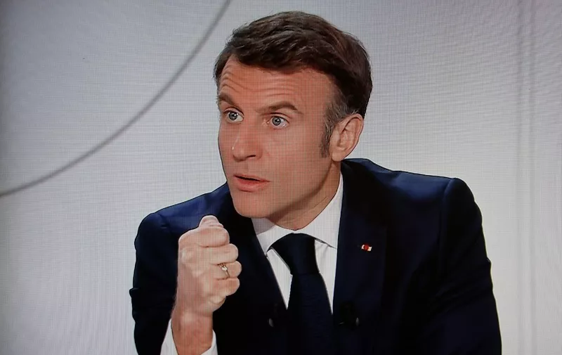 This photograph taken on March 14, 2024, shows a television screen broadcasting France's President Emmanuel Macron addressing a live interview on French TV channel France 2 at the Elysee Presidential Palace in Paris. Emmanuel Macron said on March 14, 2024, that France would "never" take the initiative to fight Russia, although he confirmed that no option should be ruled out in support of Ukraine. (Photo by Ludovic MARIN / AFP)