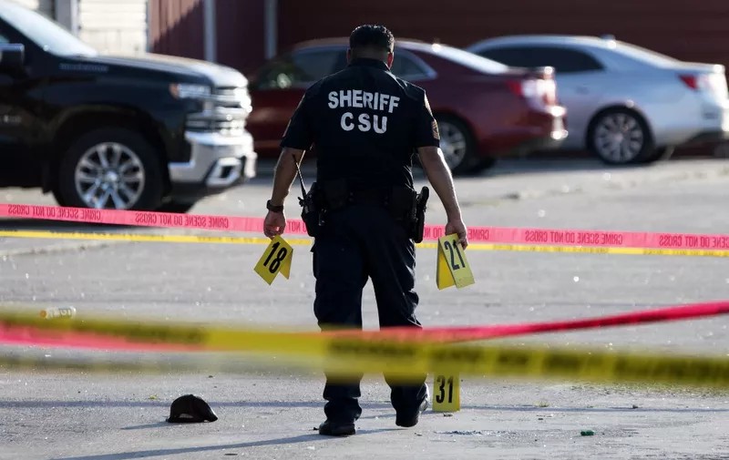 A police officer investigates a crime scene where two people were killed and three more critically injured in a shooting at a flea market in Houston, Texas on May 15, 2022. - Two people were killed and three more were taken to a hospital with injuries after a shooting May 15, 2022 at a bustling Houston flea market, authorities said. The shooting at the open-air market arose from an "altercation" that involved at least two guns and all five of the people, according to Harris County Sheriff Ed Gonzalez. He said no "innocent bystanders" were injured. (Photo by Mark Felix / AFP)