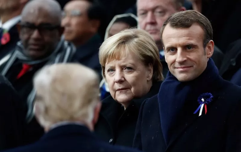 German Chancellor Angela Merkel (C) and French President Emmanuel Macron (R) react as US President Donald Trump (front L) arrives to attend a ceremony at the Arc de Triomphe in Paris on November 11, 2018 as part of commemorations marking the 100th anniversary of the 11 November 1918 armistice, ending World War I. (Photo by BENOIT TESSIER / POOL / AFP)