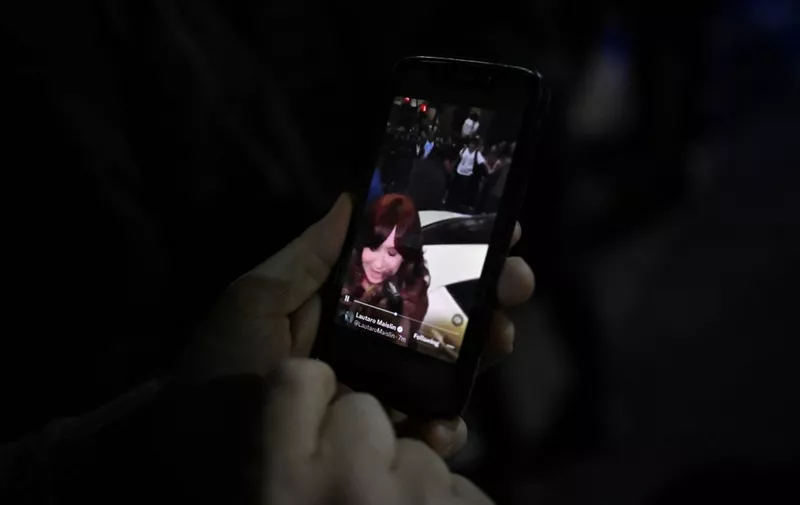 A person watches a video on a mobile phone showing a man pointing at Argentine Vice-President Cristina Fernandez de Kirchner outside her residence in Buenos Aires on September 1, 2022. - A man was arrested Thursday in Argentina for pointing a gun at Vice-President Cristina Kirchner as she arrived at her home, said Security Minister Aníbal Fernández. (Photo by Luis ROBAYO / AFP)