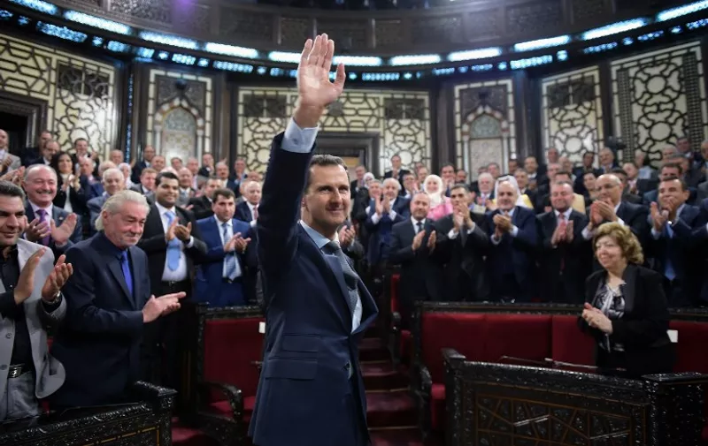 A handout picture released by the official Syrian Arab News Agency (SANA) on June 7, 2016 shows Syrian President Bashar al-Assad waving before addressing the new parliament in Damascus.
Assad addressed the new parliament in a speech broadcast on state television congratulating lawmakers on a record turnout in an April general election. Assad's last address to parliament was in June 2012, just after general elections in May of that year. / AFP PHOTO / SANA / HO / RESTRICTED TO EDITORIAL USE - MANDATORY CREDIT "AFP PHOTO / HO / SANA" - NO MARKETING NO ADVERTISING CAMPAIGNS - DISTRIBUTED AS A SERVICE TO CLIENTS