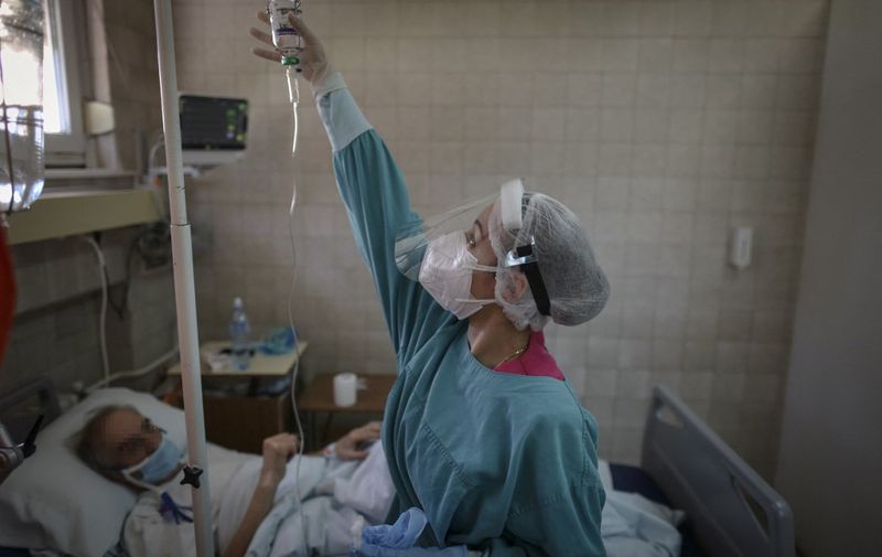 Medical worker checks a drip for a patient suffering from coronavirus disease, Covid-19, inside the KBC Zvezdara Hospital in Belgrade on March 21, 2021. (Photo by OLIVER BUNIC / AFP)