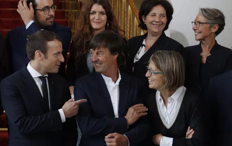 French President Emmanuel Macron (L) speaks with Ecology Minister Nicolas Hulot and Culture Minister Francoise Nyssenas as they pose with members of the government for a family photo at the Elysee Palace in Paris, May 18, 2017. Left to right second row: Junior Minister for digital Mounir Mahjoubi, Junior Minister for disabeled people Marlene Schiappa, Higher Education Minister Frederique Vidal and Transport Minister Elisabeth Borne.  / AFP PHOTO / POOL / PHILIPPE WOJAZER