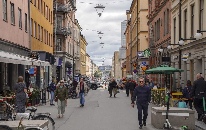 This picture taken in Stockholm, Sweden, on August 31, 2020, shows people walking in a street in Stockholm, amid the novel coronavirus pandemic. - While most of the world has come to terms with covering their noses and mouths in crowded places as a measure to prevent the spread of Covid-19, Sweden continues to refuse to recommend the use of masks. (Photo by Tom LITTLE / AFP)
