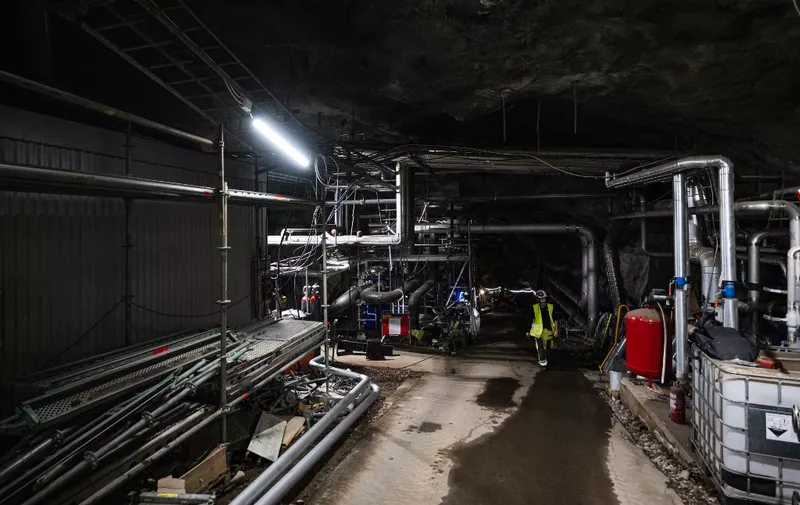 A worker walks at the site of a former oil storage cavern, on August 11, 2023, in Västeras, Sweden, which is repurposed by Swedish energy company Mälarenergi and to be turned into a hot water storage facility. Mälarenergi, a Swedish energy company that provides various energy services to the region surrounding Lake Mälaren, is repurposing the former oil storage cavern into a massive energy storage facility for district heating, set to become Europe's largest hot water storage at temperatures reaching 95 degrees Celsius, with a capacity of 300,000 cubic meters, upon its 2024 completion. (Photo by Jonathan NACKSTRAND / AFP)