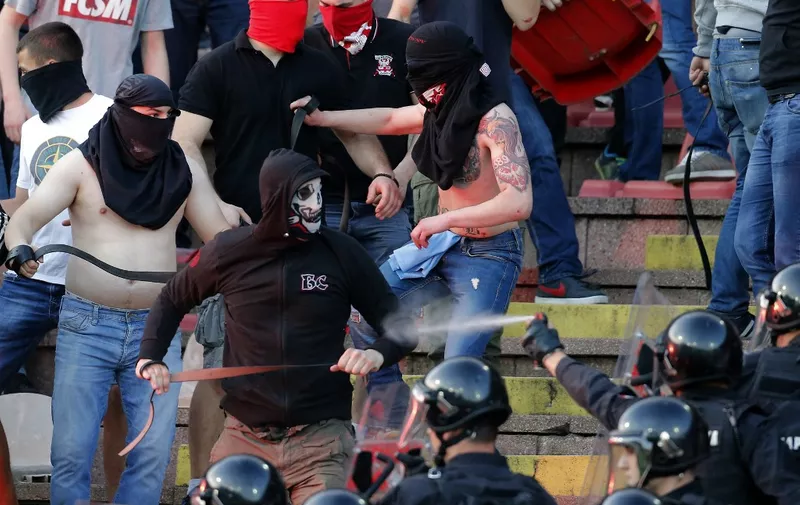 A picture taken on April 16, 2016 shows supporters of Red Star Belgrade clashing with police on the tribunes during the Serbian first league match between Red Star and Partizan, in Belgrade. An "Eternal Derby" tainted by ultranationalism: the recurring duel between Belgrade's Partizan and Red Star, which next takes place on March 4, 2017 has become more about hooligans and police than sport. Nowadays a pretext for clashes between supporters of the rival teams, the event was for a long time a celebration of Yugoslav football, which had a certain romantic aura despite a lack of trophies. But that golden era of football collapsed with the breakup of Yugoslavia in the bloody conflicts of the 1990s. (Photo by PEDJA MILOSAVLJEVIC / AFP)